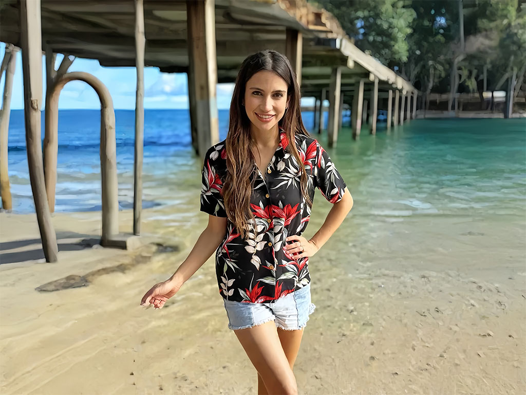 A woman pairs a Hawaiian shirt with denim shorts for a beach day.
