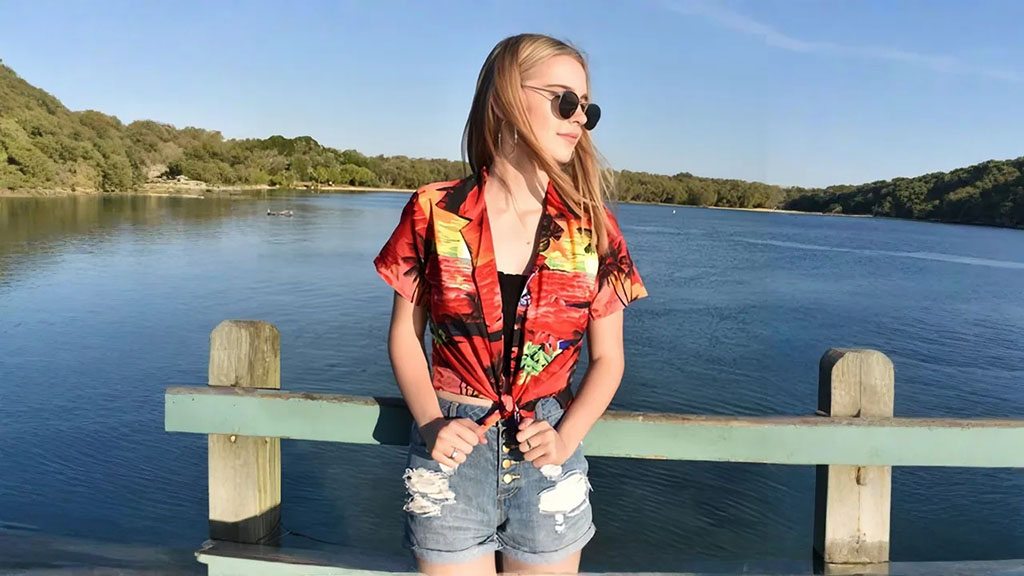 A woman enjoys a summer day at the beach, wearing a vibrant Hawaiian shirt.