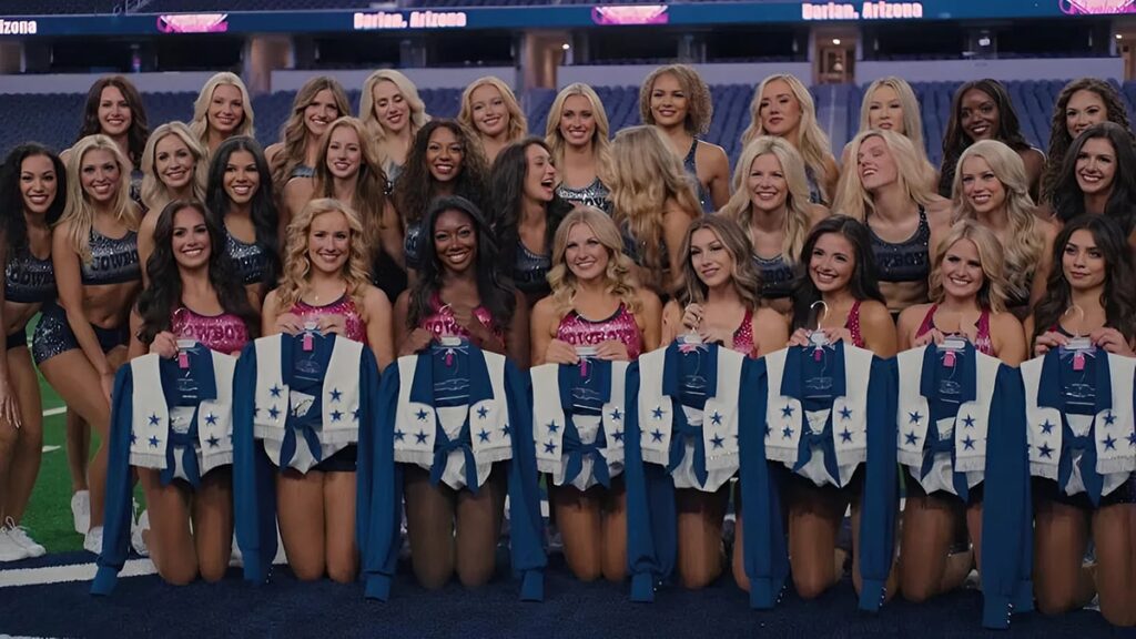 Dallas Cowboys Cheerleaders posing together on the field, proudly holding their iconic star studded uniforms