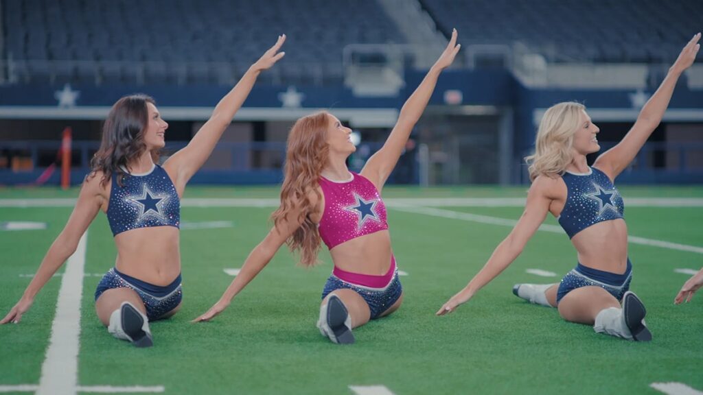 Three Dallas Cowboys cheerleaders posing on the field in star themed uniforms