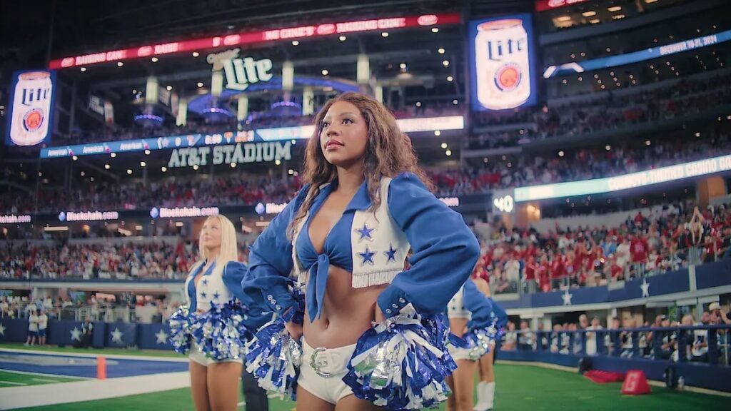 Dallas Cowboys cheerleader standing confidently on the field at AT&T Stadium during game day