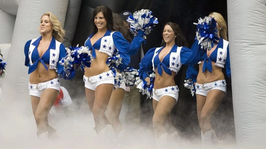 Dallas Cowboys Cheerleaders entering the field with energy and pom poms through stadium fog